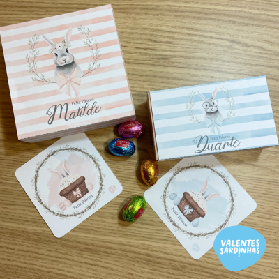 Caixas de presente decorativas com tema de Páscoa, chocolates coloridos e etiquetas com ilustração de coelho sobre superfície de madeira