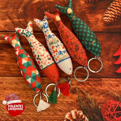 Cinco porta-chaves em forma de sardinha com padrões diversos e fundo de madeira natalício