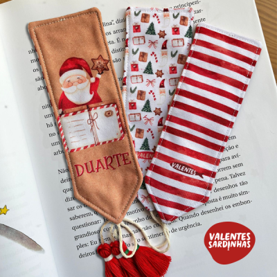 Três marcadores de livros natalícios em tecido, um com Pai Natal, outro com padrões natalinos e outro às riscas vermelhas e brancas