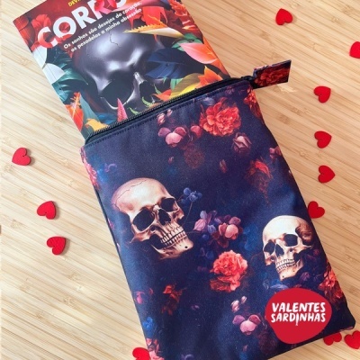 Estojo com padrão de caveiras e flores e embalagem com palavra CORPO em fundo de madeira com corações vermelhos