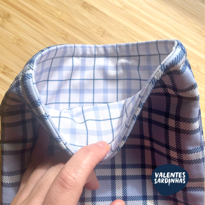 Lenço branco e azul xadrez segurado por uma mão sobre madeira clara com logótipo VALENTES SARDINHAS