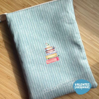 Saco de tecido azul claro com riscas verticais e desenho de pilha de livros