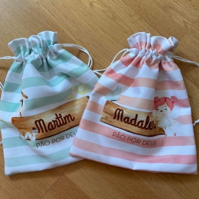 Dois sacos de tecido com cordão, riscas coloridas e nomes Martin e Madalen com texto PÃO POR DEUS.