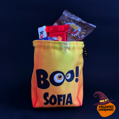 Saco tecido amarelo com texto 'BOO! SOFIA' e chocolates dentro sobre fundo preto