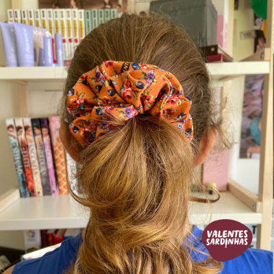 Scrunchie laranja com padrão floral em cabelo castanho