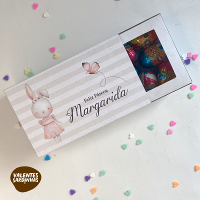 Caixa de chocolates com design de coelho e texto Feliz Páscoa Margarida, rodeada por confetes coloridos em forma de coração