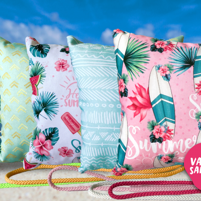Almofadas tropicais com padrões florais, geométricos e de melancia em fundo azul celeste.