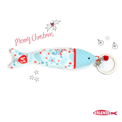 Porta-chaves em forma de peixe azul claro com padrões vermelhos e argola metálica.