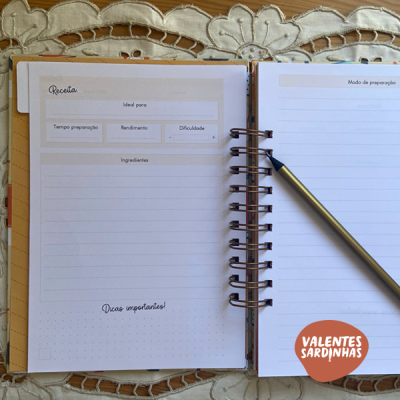 Livro de receitas aberto com caneta sobre toalha bordada