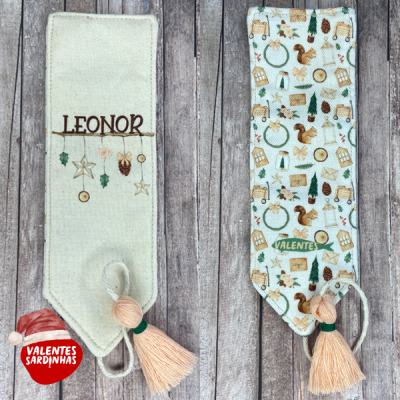 Duas capas de tecido com decoração natalícia, uma com nome LEONOR e outra com padrão colorido e texto VALENTES