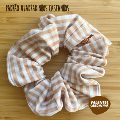 Elástico de tecido castanho com padrão quadriculado sobre fundo de madeira clara