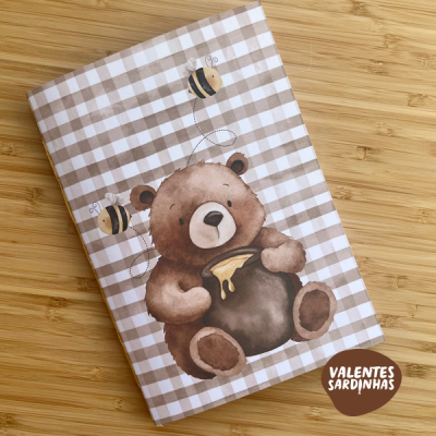 Caderno com capa com padrão xadrez e urso a segurar pote de mel