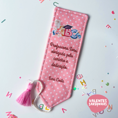Marca-páginas rosa com estrelas brancas, texto dedicado a professora Sara, tassel rosa e decoração ABC colorida em fundo branco.