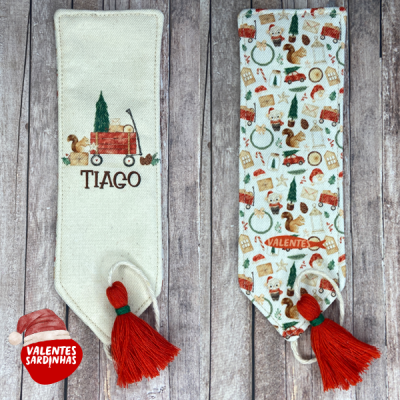 Dois marcadores de livros natalícios em tecido com tassel vermelho, um creme com bordado personalizado e outro com padrão colorido