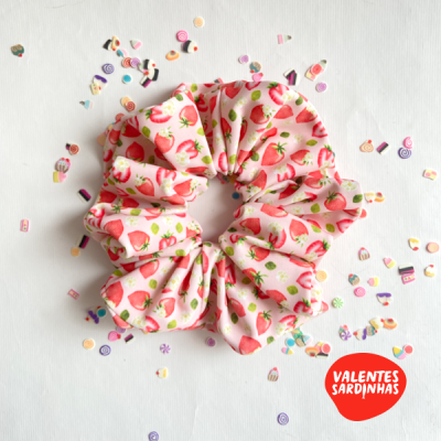 Elástico para cabelo rosa com padrão de morangos sobre fundo branco com confeitos coloridos