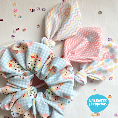 Elásticos de cabelo infantis com padrões coloridos e orelhas de tecido sobre fundo branco com confetes