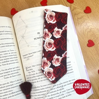 Marcador de livros com padrão de rosas vermelhas e brancas sobre livro aberto