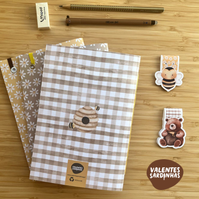 Conjunto de cadernos e material escolar com desenhos de abelha, urso e padrões xadrez em tons de bege e branco