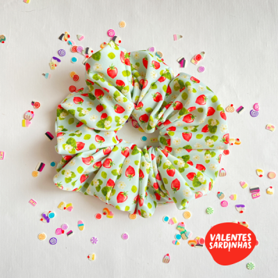 Elástico para cabelo com padrão de morangos sobre fundo azul claro e enfeites coloridos