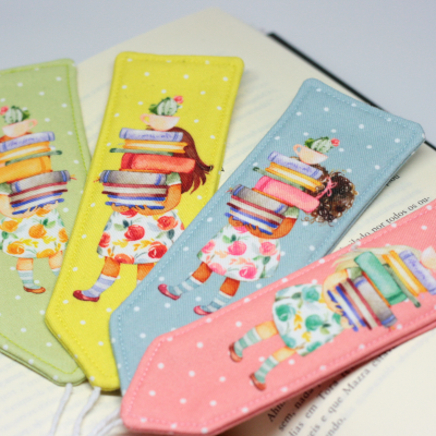 Marcadores de livros coloridos em tecido com desenho de menina a carregar livros e cacto.