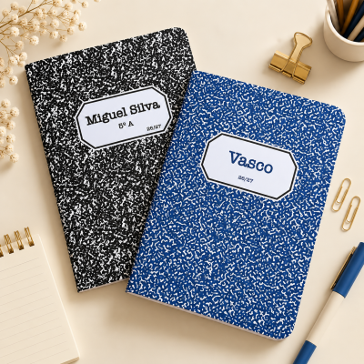 Dois cadernos com capas preta e azul com texto personalizado sobre mesa bege com acessórios de escritório.