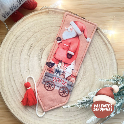 Marcador de livros rosa com Pai Natal e nome SOFIA, pendente com tassel vermelho sobre base de madeira