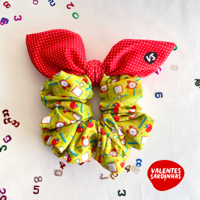 Elástico de cabelo scrunchie amarelo e vermelho com padrões de relógios, maçãs e cadernos, sobre fundo branco com números coloridos dispersos