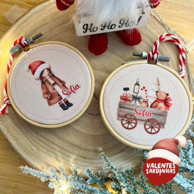 Bastidores de bordado com desenhos infantis natalícios e nome Sofia, sobre mesa de madeira, com decoração natalícia.
