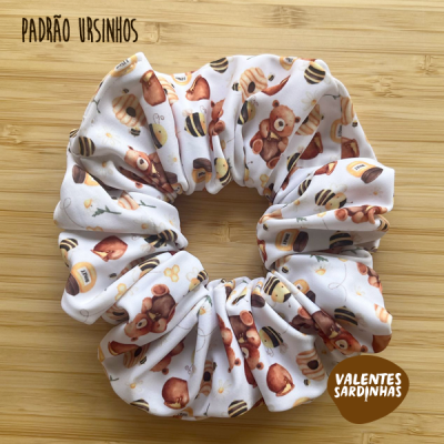 Scrunchie branco com padrão de ursinhos e abelhas sobre madeira
