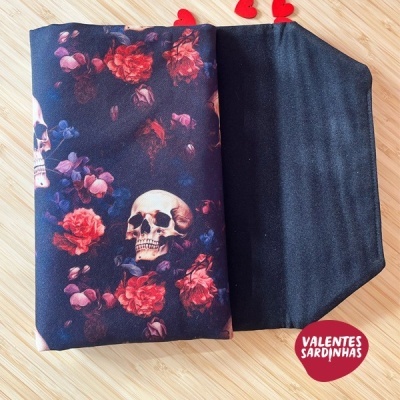 Lenço com padrão de caveira e flores em fundo preto sobre madeira clara com selo vermelho VALENTES SARDINHAS.