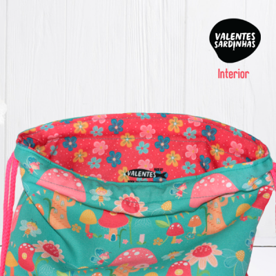 Saco colorido com padrão de cogumelos e flores e interior vermelho com pequenas flores.