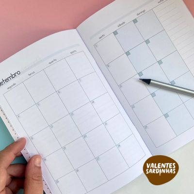 Calendário mensal aberto em setembro com caneta e mão segurando página