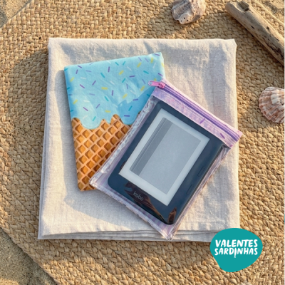 Leitor digital Kobo numa bolsa transparente com capa de casquinha de gelado sobre tecido bege e tapete de palha