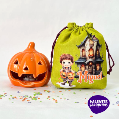 Lanterna em forma de abóbora laranja ao lado de saco de tecido verde com ilustração Halloween e nome Miguel