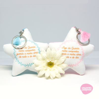 Porta-chaves em forma de estrela branca com texto em português e tassel azul e rosa
