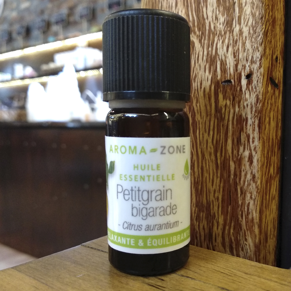 Óleo essencial de Laranja Amarga / Petitgrain Frasco de óleo essencial Petitgrain bigarade da Aroma-Zone com tampa preta sobre superfície de madeira