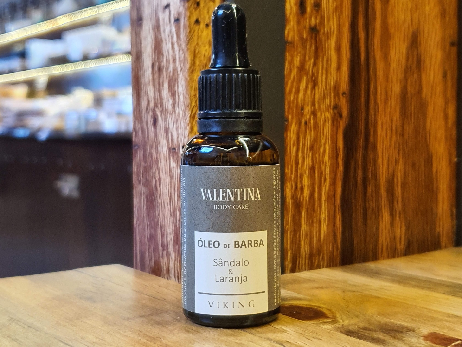 Óleo Natural Para Barba Sândalo & Laranja frasco de óleo de barba Valentina em mesa de madeira com fundo de madeira
