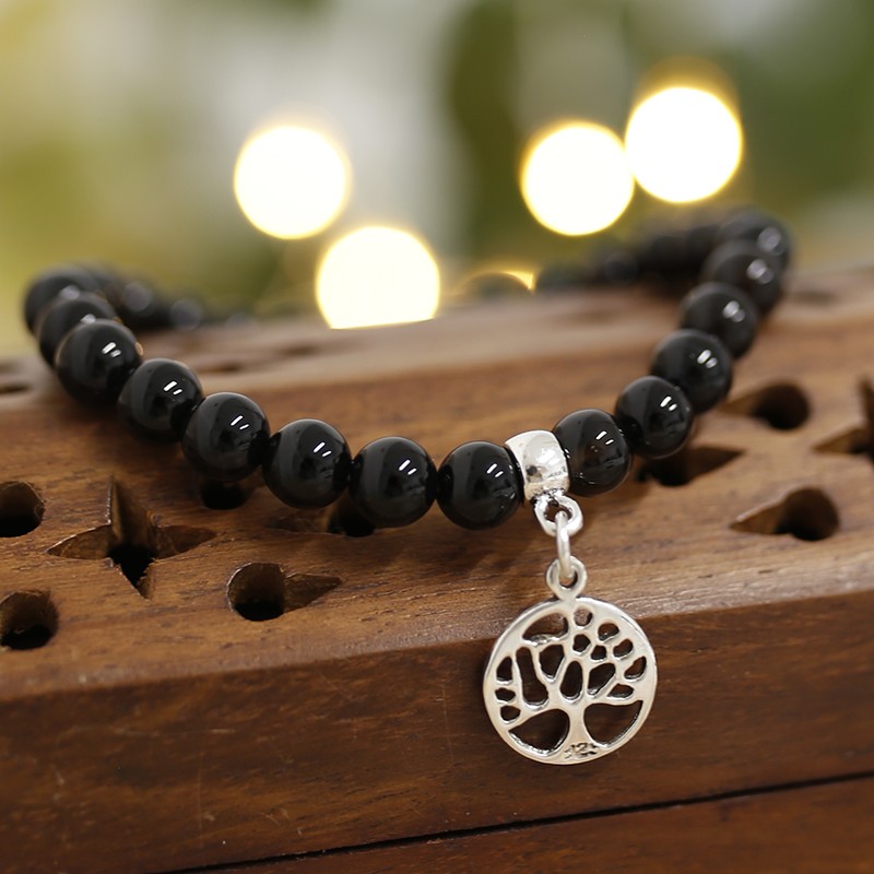 Pulseira de Ónix Com Árvore da Vida de Prata Pulseira de contas pretas com pendente de árvore da vida sobre madeira