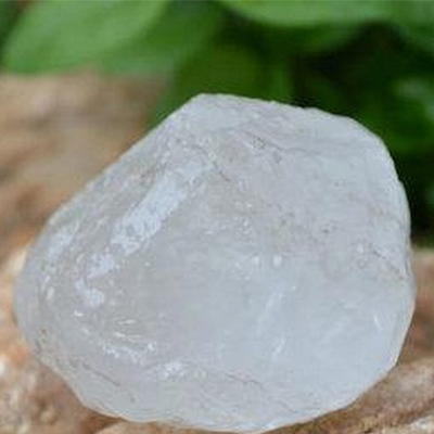 Desodorizante Pedra de Alúmen em Bruto Pedra branca translúcida com textura irregular sobre superfície natural