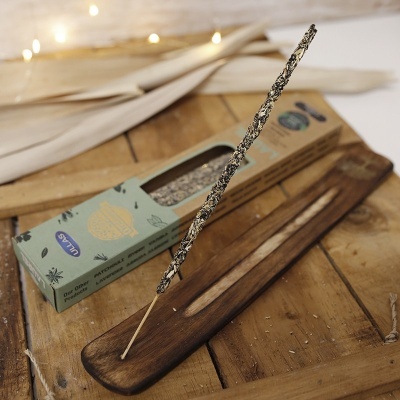 Incenso tópico em pau de madeira numa base de madeira com caixa de papel verde