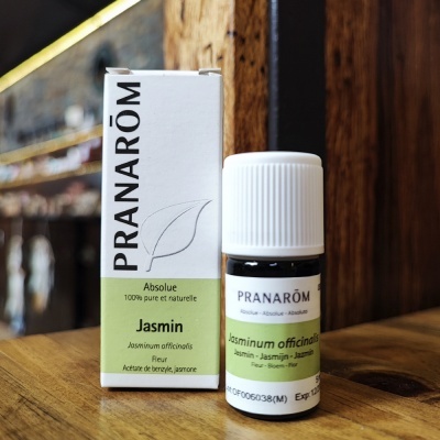 Frasco e caixa de óleo essencial PRANARÔM Absolue Jasmin sobre mesa de madeira