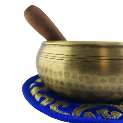 Tigela tibetana dourada com bastão de madeira em almofada azul bordada