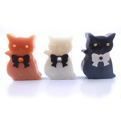 Figuras de gato em resina laranja, branca e preta com laços e pedrinhas brilhantes.