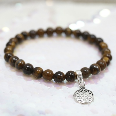 Pulseira de contas de pedra marrom com pendente prateado sobre superfície branca brilhante