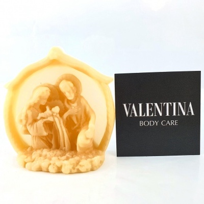 Vela creme decorativa da Sagrada Família ao lado de cartão preto com texto 'VALENTINA BODY CARE'