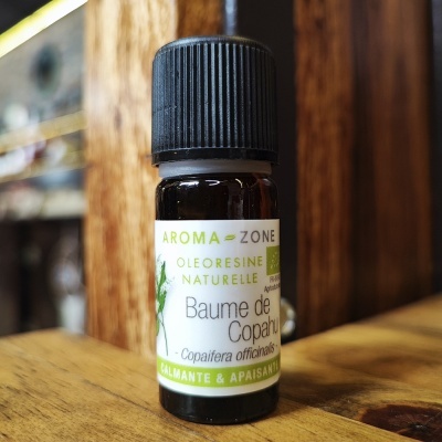 Frasco pequeno de vidro castanho com etiqueta branca e verde sobre superfície de madeira