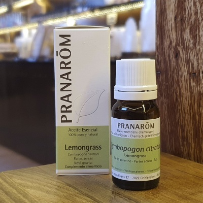 Frasco e embalagem de óleo essencial Lemongrass da marca PRANARÔM sobre mesa de madeira