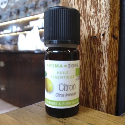 Frasco de óleo essencial de limão AROMA-ZONE sobre mesa de madeira