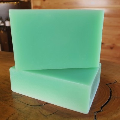 Dois sabonetes verdes empilhados sobre madeira com fundo de parede e prateleira