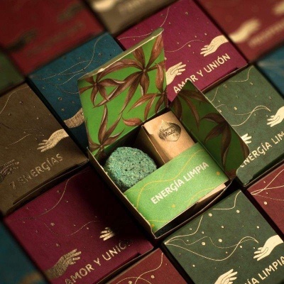 Caixas coloridas com textos diversas e uma caixa aberta com bola azul e embalagem cilíndrica.